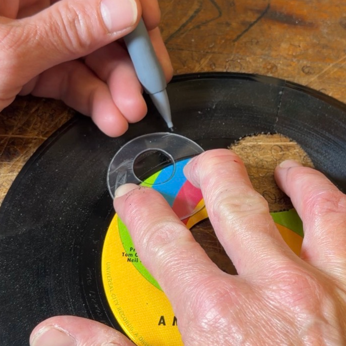 Handmade clear template being positioned on a vinyl record